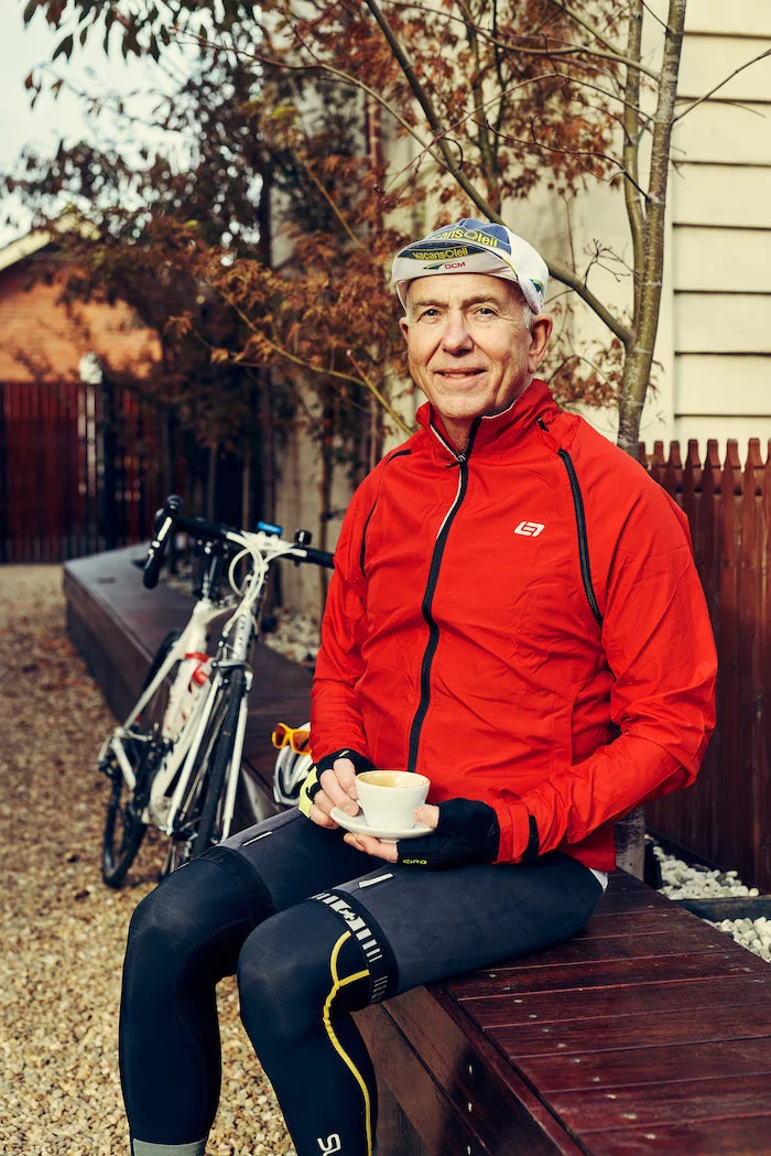 Alwyn sitting down with coffee with bike leaning against bench in the background