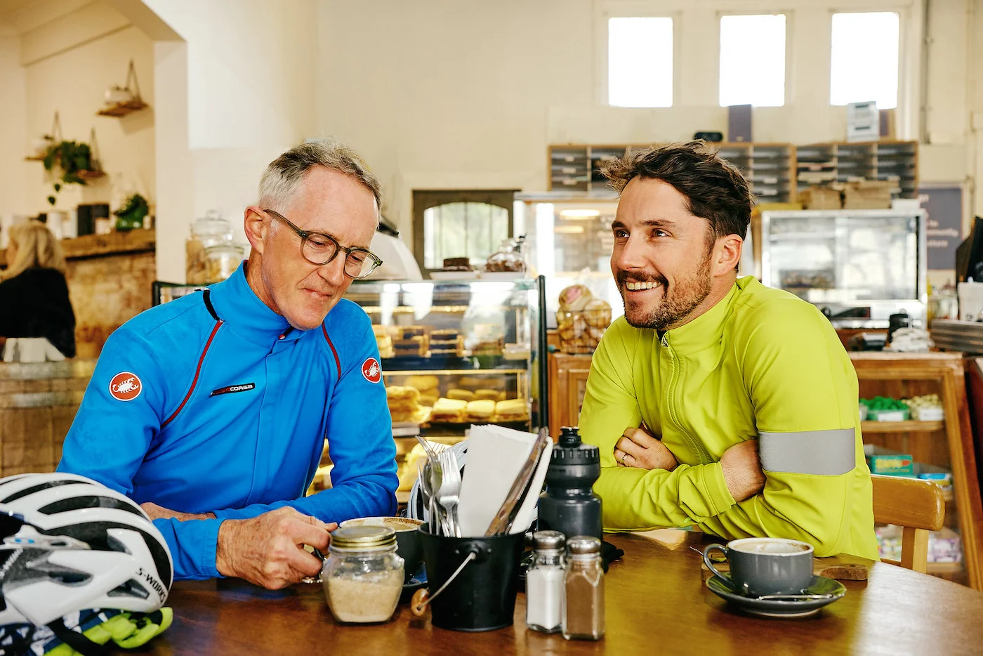 Julian and his dad sitting at a cafe laughing and enjoying their coffee